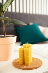 Scandinavian interior, yellow honey scented beeswax candle on bedroom cabinet