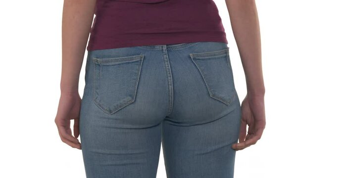 Rear view of unrecognizable Caucasian woman in jeans grabbing her buttocks because of discomfort feeling. Healthcare concept. Isolated on white background