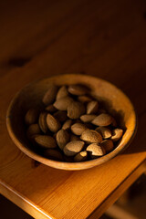Almonds in a wooden bowl with slither of light