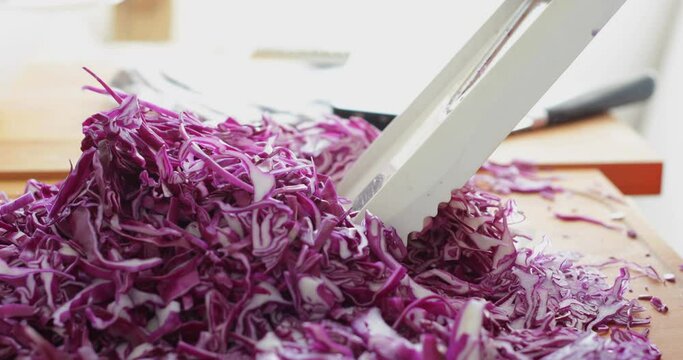 Red cabbage cut into thin slices using kitchen mandoline slicer, sauerkraut making process, close up