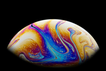 Half a soap bubble. An iridescent swirl of colors. Isolated on black background. Close-up.