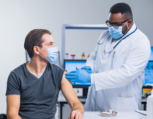 African-American doctor makes a coronavirus vaccine using a syringe and hypodermic needle....