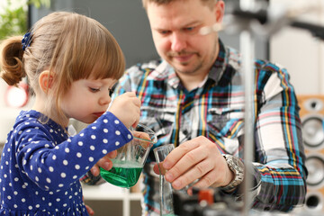 Man and little girl play with colourful liquids portrait. Young team clean research equipment...