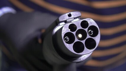 Close up a plug that charges electric cars. Black high-voltage wire with copper contacts. Charging of electric car. Electric Hybrid. The battery indicator. Eco energy, transport and power supply 4K