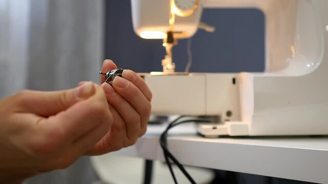 Close-up of threading the bobbin of the sewing machine. Needlework concept.