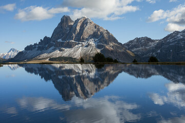 Sass de Putia reflects itself over a small alpine lake in Dolomites at evening