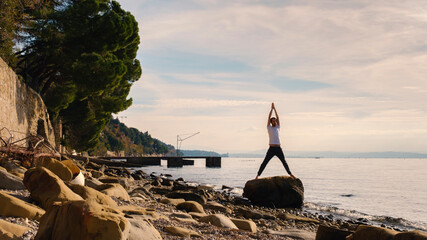 Attractive young man practicing yoga meditation and breathwork outdoors by the sea