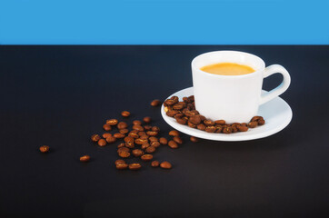 A cup of espresso coffee, a bunch of toasted coffee beans on a dark background.