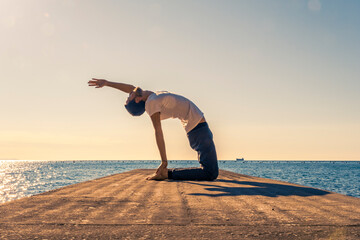 Attractive young man practicing yoga meditation and breathwork outdoors by the sea