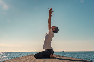 Attractive young man practicing yoga meditation and breathwork outdoors by the sea