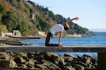 Attractive young man practicing yoga meditation and breathwork outdoors by the sea