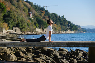 Attractive young man practicing yoga meditation and breathwork outdoors by the sea