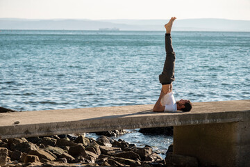 Attractive young man practicing yoga meditation and breathwork outdoors by the sea