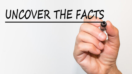 the hand writes text UNCOVER THE FACTS with a marker on a white background. business concept