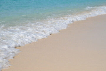 Fototapeta na wymiar Waves gently lapping on to golden sand on a beautiful tropical beach.