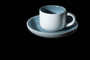 A blue and white coffee cup paired with a saucer on a black background.
