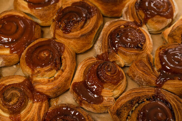 Homemade cinnamon buns with spices and caramel on parchment paper.