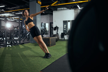 Fototapeta na wymiar Cheerful brunette sportswoman using equipment for training