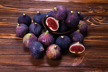 Tasty figs in a bowl on wooden background. Top view.