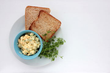 Egg salad sandwich with whole wheat toasted bread and microgreens on plate on white background. Healthy food concept
