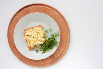 Egg salad sandwich with whole wheat toasted bread and microgreens on plate on white background. Healthy food concept
