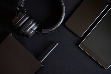 Black router and wireless gadgets - smartphone, tablet and headphones on a dark background....