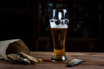 Glass of beer and dried fish on a wooden table