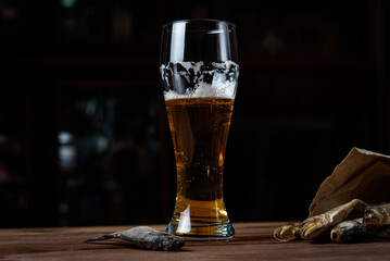 Glass of beer and dried fish on a wooden table