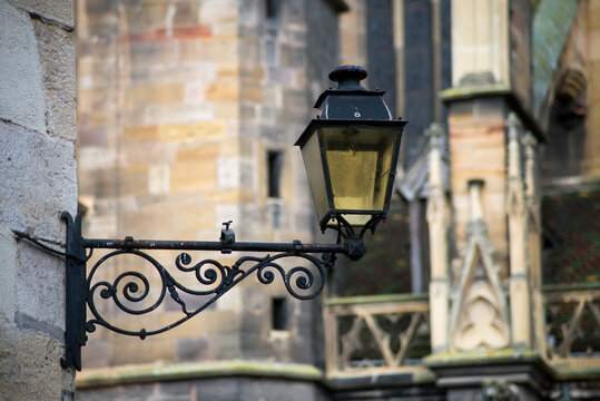 Closeup of vintage street light on medieval cathedral on background in Colmar in France