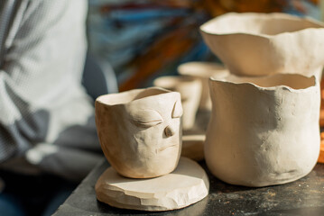 young artist moulding raw clay in art studio. Girl molds from clay sculpture in the artist's studio. Business woman at her pottery store