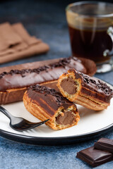 Chocolate eclairs on a white plate. Traditional french dessert. Eclair cutaway. Selective focus 