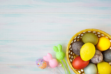 Colored Easter eggs with decor in a wicker yellow basket. Empty space for text