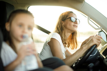 Fototapeta na wymiar Donna al volante con maglietta bianca in contesto vacanziero viaggia con la figlia con espressioni sorridenti