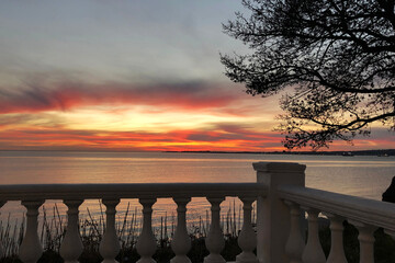 scenery sunset on sea embankment with fence, tree is near. Beautiful tranquil evening, wallpaper,...