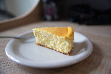 piece of new york cheesecake on a white plate with fork. Depth of field