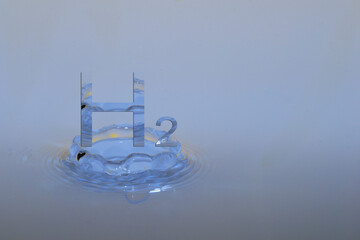 hydrogen h2 letters over a drop impact in a blue fluid