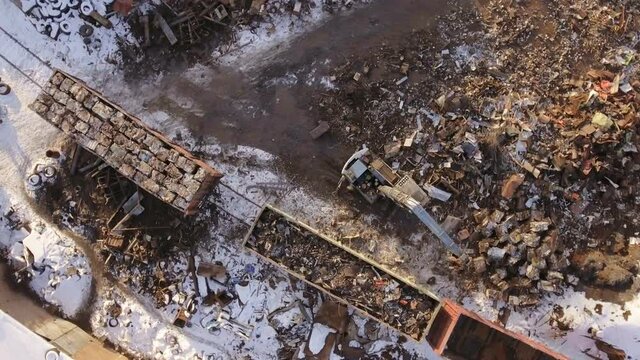 Aerial photography of scrap metal dump, Crane unloads, loads scrap metal in a railway car.