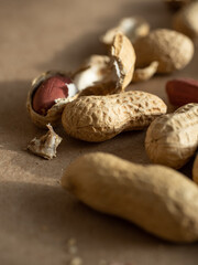 Peanuts in shells and peeled scattered on brown craft paper in the morning light