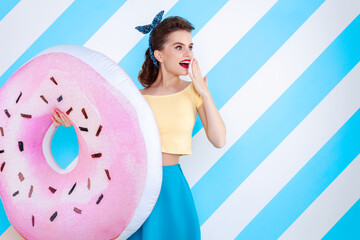 Sexy surprised woman with donuts in hands and open mouth. Colorful background in pop art retro comic style on striped blue background. Pinup and pop art concept