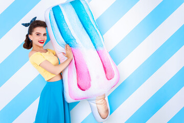 Sexy surprised woman with ice-cream in hands and open mouth. Colorful background in pop art retro comic style on striped blue background. Pinup and pop art concept