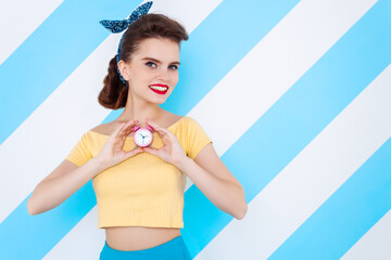 Sexy surprised woman with alarm clock in hands and open mouth. Colorful background in pop art retro comic style on striped blue background. Pinup and pop art concept