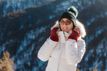 People on the background of beautiful nature. Sunny weather in the mountains. The girl in winter clothes smiles looks into the frame. 