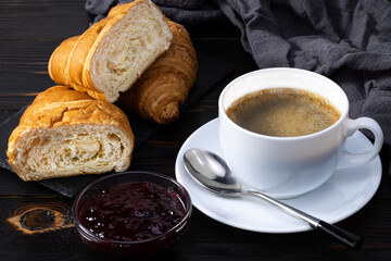 fresh croissants with jam and coffee on dark background. French breakfast