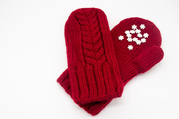 A knitted red mittens with white snowflakes on a white background, isolated. Concept of Christmas, winter, love. Care and Valentines day. Copy space