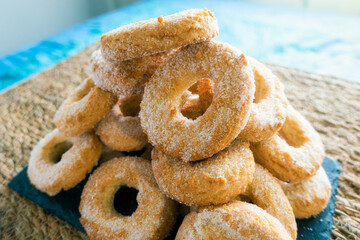 Sweet donuts with sugar, piled on a hemp tray with soft light.