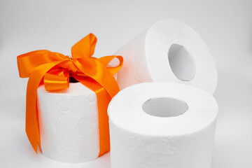 Several rolls of white perforated toilet paper. One roll is tied with a bright orange satin ribbon as a gift