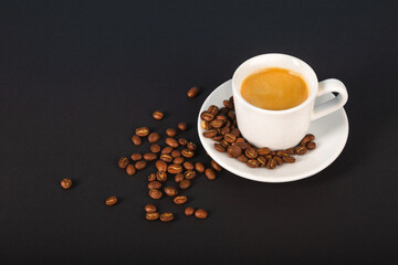 A cup of espresso coffee, a bunch of roasted coffee beans on a dark background. View from above.