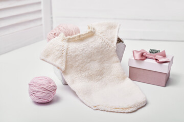 Needlework and knitting. Hobbies and creativity. Knit for children. Knitted toys rabbit, bodysuit and hat. Handmade toy hare. Baby cap. Yarn, threads and balls