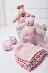 Needlework and knitting. Hobbies and creativity. Knit for children. Knitted toys rabbit and hat. Handmade toy hare. Baby cap. Yarn, threads and balls