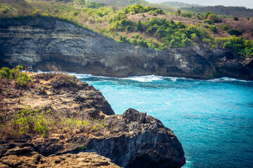Group of people stand on a cliff and look out over the rough sea. Photo was taken near Broken Beach,Nusa Penida Island, Klingung regency, Bali, Indonesia. 